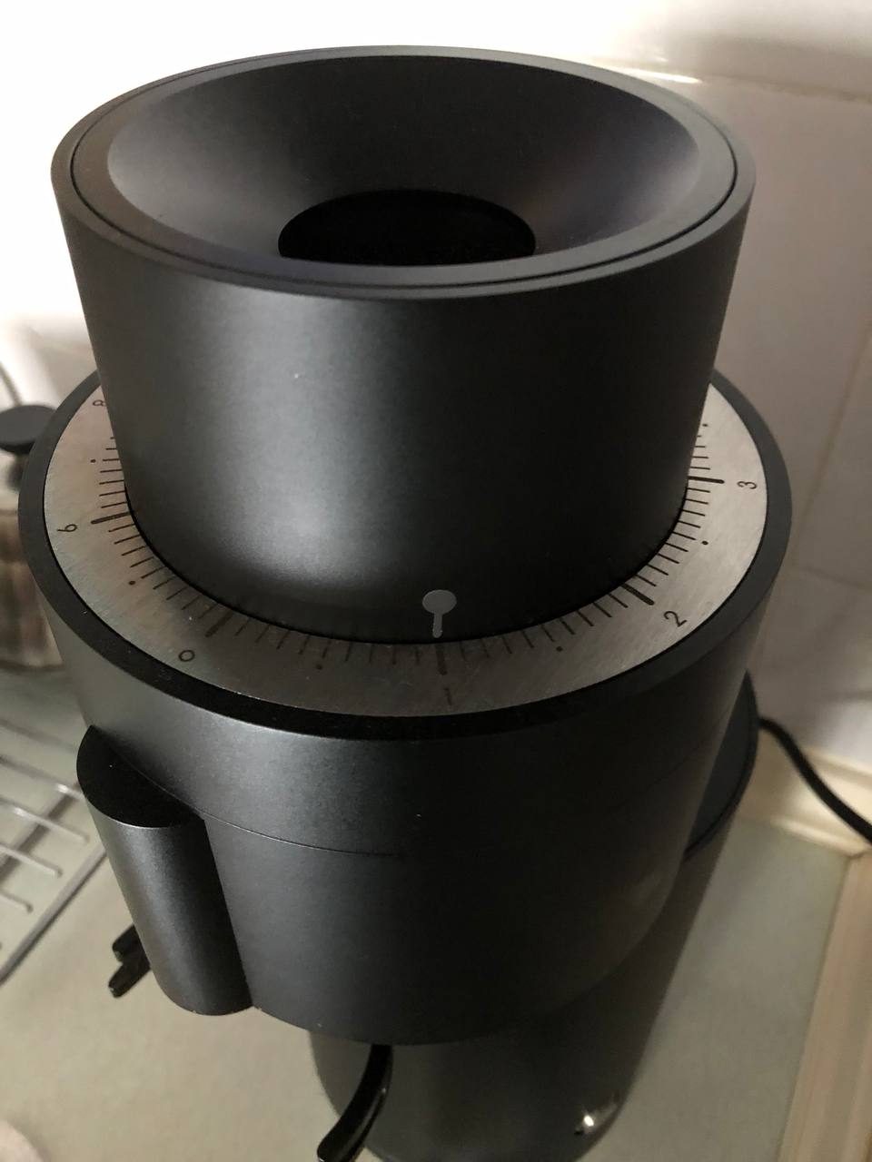 The P100's open bean intake funnel has a sticker with an arrow that points to the current grind size. There is a number scale that runs along the outer edge of the funnel numbered 0 to 9 with smaller lines for increments of 0.1 between each number.